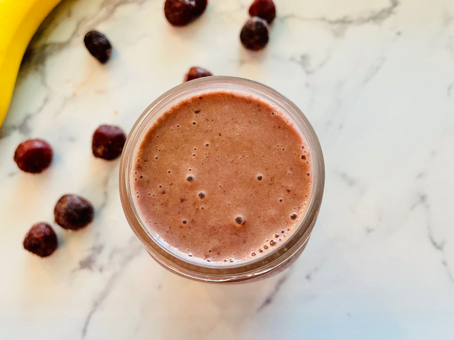 A tall mason cup full of elderberry cherry smoothie sitting on marble counter