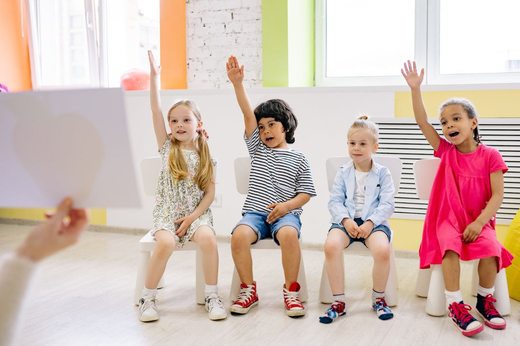 Kids in school setting raising their hands.
