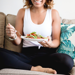 mind-body connection, person sitting on a couch eating fresh foods and joyful